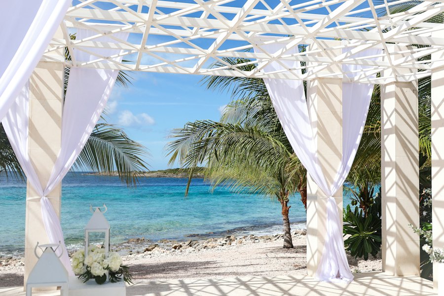 Arco de boda en la playa mirando al mar turquesa, sin gente. Sirve para bodas destino sin comprometer a nadie.