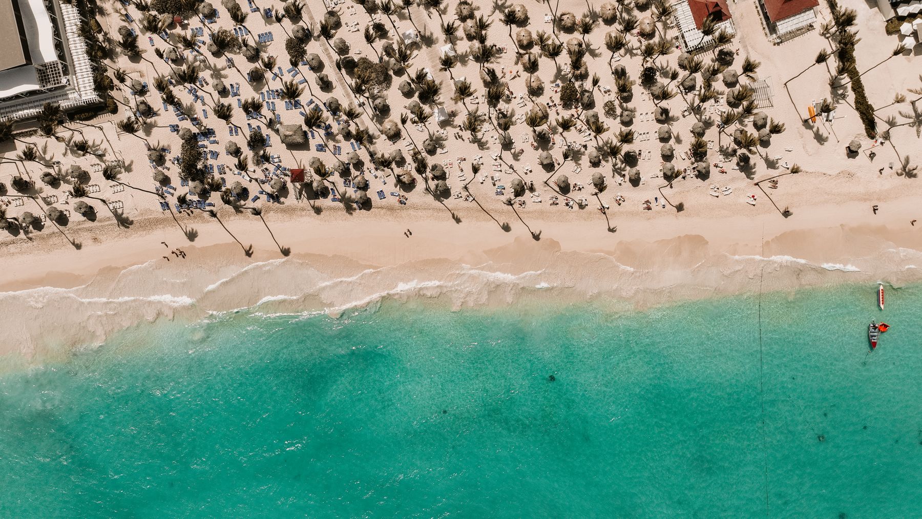Toma con dron de arena blanca y agua en República Dominicana. Formato muy panorámico (16:9), ideal para banda de portada.