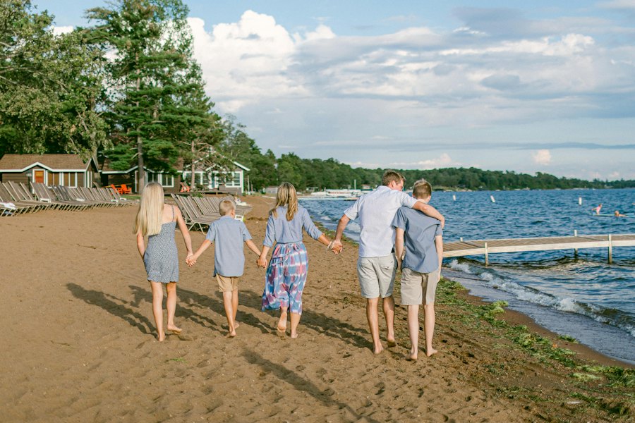 Familia caminando de la mano por la playa, de espaldas.